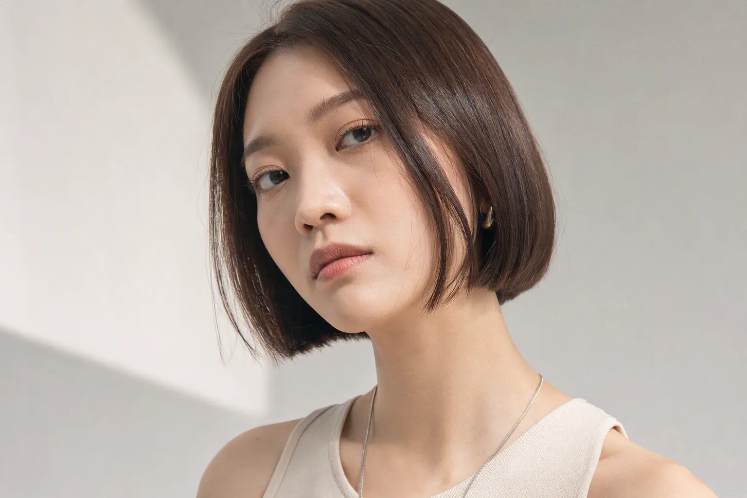 齊下巴短髮女生正面對鏡頭,露出臉型線條,米色背景